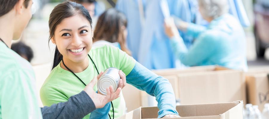 A woman holds a perishable food can at a food drive event.